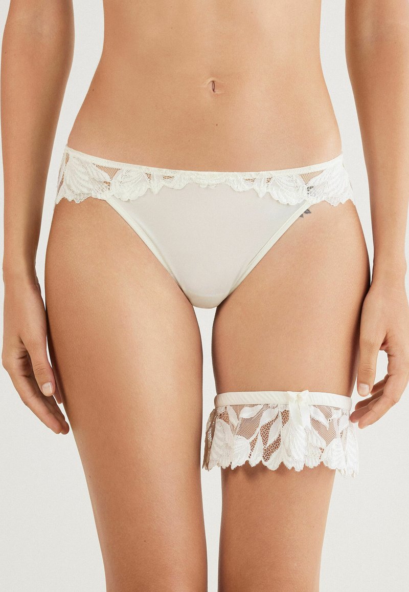 Witte kanten hipster onderbroeken met een bloemenkant rand en een bijpassende kanten kousenband met een lintdetail. Glad materiaal en delicate textuur.