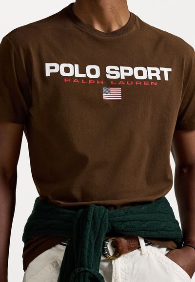Camiseta de algodón marrón con la leyenda "POLO SPORT" y "RALPH LAUREN" en texto blanco y rojo, con un pequeño gráfico de la bandera americana.