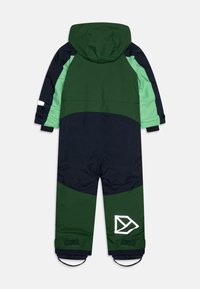 Zaļš un jūras zils ūdensnecaurlaidīgs sniega kostīms ar kapuci, elastīgām aprocēm un atstarojošu logo akcentu. Iezīmē krāsu blokiem veidotu dizainu un izturīgu audumu.