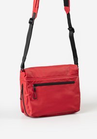 Borsa a tracolla rossa realizzata in materiale liscio. Presenta una tracolla nera regolabile e una tasca anteriore con zip nera. Forma rettangolare compatta.