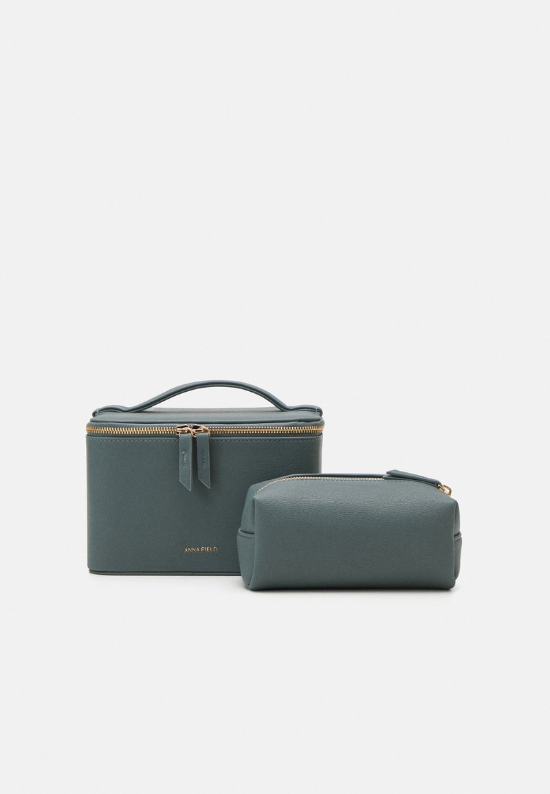 Two soft-textured, teal cosmetic bags in rectangular and cylindrical shapes, featuring gold zipper hardware and a brand engraving.
