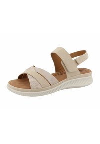Beige sandal with cross straps made of textured and smooth materials, cushioned sole, and adjustable ankle strap. Low-profile design.