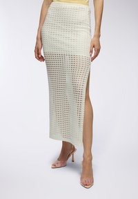 Gonna al ginocchio realizzata in un leggero tessuto a maglia testurizzato con motivo a griglia; presenta uno spacco laterale fino alla coscia e una vita elasticizzata.