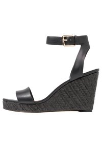 Černé wedges sandály s texturovanou tkáňovou platformou, s hladkým koženým páskem a nastavitelnou sponou, které mají elegantní, moderní design.