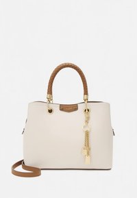 Sac à main crème avec poignées tressées marron, ferrures dorées et une chaîne décorative avec des cadenas. Dispose de poches latérales et d'une forme structurée.