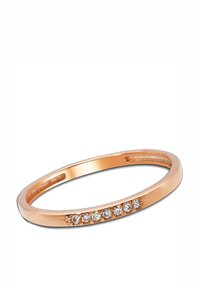 Bague en or rose avec une surface lisse et polie, ornée de sept petites pierres précieuses claires alignées sur un côté.