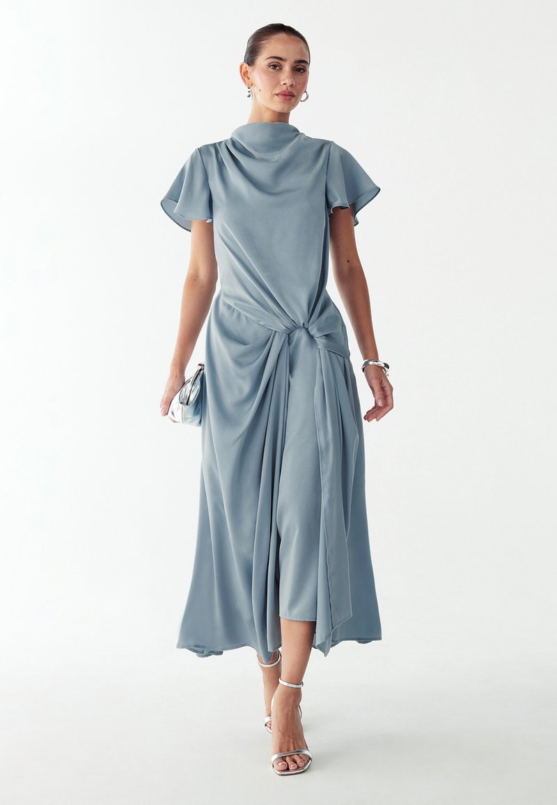 Hele sinine midi-kleit sõlmitud detailiga vööl, lühikeste lendlevate varrukatega ja siledalt satiinilaadse tekstuuriga. Hõbedased aktsendid täiendavad välimust.