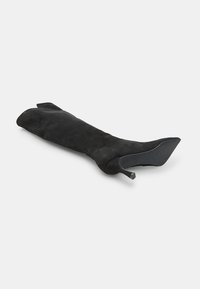 Svart mocka lång stövel med spetsig tå och tunn, vinklad klack. Slät yta utan synliga mönster eller detaljer i hårdvara.