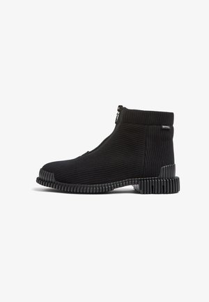 Black knit ankle boots with a zipper closure, textured upper, and a ridged rubber sole, emphasizing a sleek and modern design.