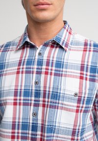 Geruite shirt met blauwe, rode en witte checkpatronen. Gemaakt van lichte stof, het heeft een button-down kraag en een borstzak.