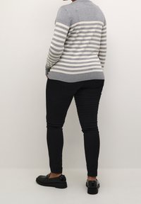 Pull rayé gris à col rond, manches longues, associé à un pantalon noir ajusté et des mocassins noirs. Texture lisse, design décontracté.