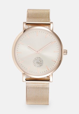 Runde Uhr mit einem Gehäuse aus Roségold, silbernem Zifferblatt und Kristallverzierung in der Mitte. Verfügt über ein Roségold-Mesh-Armband.