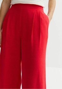 Red wide-leg trousers with pleats at the waist, made of lightweight fabric. Features side pockets and a smooth texture.