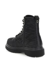 Bota de combate negra con patrón texturizado en ondas, parte delantera con cordones, cremallera lateral, suela gruesa y estriada, y pequeño logo metálico cerca de la parte superior.