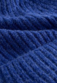Tissu en maille bleu profond, présentant une texture côtelée avec des fibres visibles, créant une apparence douce et chaude.