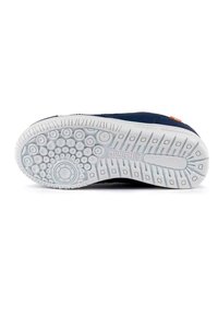 Suela de zapato con una base de goma blanca que presenta patrones circulares y cuadrados; parte superior en color azul marino con un pequeño acento naranja.