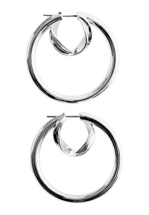 Paire de boucles d'oreilles anneaux en argent poli avec des bords lisses et arrondis et des fermetures à tige, sur fond blanc.