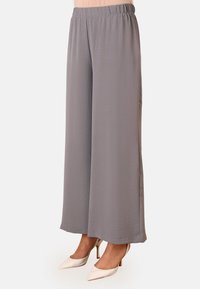 Light gray wide-leg trousers with an elastic waistband, featuring a crinkled texture and tailored hem, paired with off-white heeled shoes.