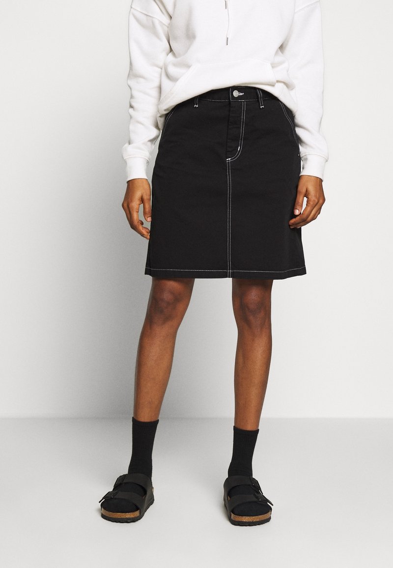 Black denim skirt with white contrasting stitching, knee-length design, front button closure, paired with black socks and sandals.