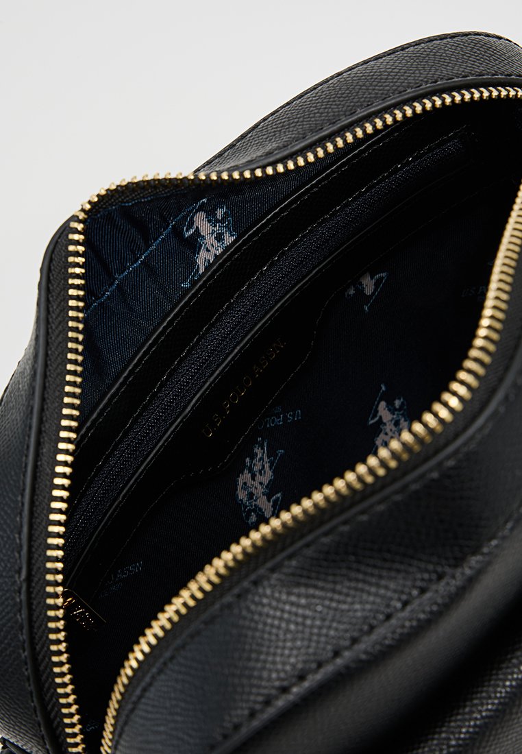 Sac à main en cuir noir avec un extérieur texturé, fermeture éclair dorée et doublure intérieure bleu foncé comportant un motif logo répété.