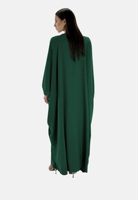Grön, flödande kaftan med långa ärmar, tillverkad av mjukt tyg, har en lös silhuett och en hög halsringning som draperar elegant framifrån.