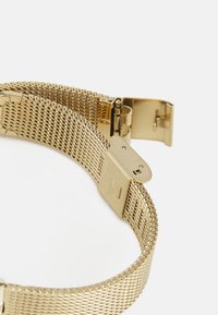 Bracciale per orologio in maglia dorata con finitura metallica lucida, dotato di una chiusura sicura e di una sezione rettangolare per la regolazione. Texture liscia in tutto il bracciale.