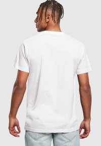 Hvid bomulds t-shirt med korte ærmer, rund hals og afslappet pasform. Bagsiden er ensfarvet uden grafik eller mønstre. Glat tekstur.