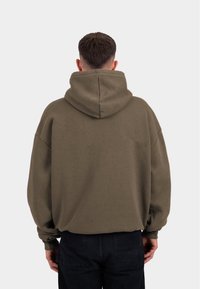 Beige Oversize-Hoodie mit großer Kapuze, gerippten Bündchen und glatter Textur, von hinten vor einem schlichten Hintergrund präsentiert.