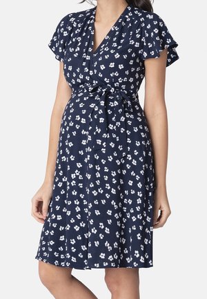 Robe portefeuille de grossesse bleu marine avec imprimé floral blanc, manches courtes volantées et ceinture à nouer à la taille.