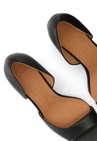 Μαύρα δερμάτινα παπούτσια μπαλαρίνες με στρογγυλεμένες μύτες και ανοιχτές πλευρές, με ταμπά εσωτερικά πέλματα που φέρουν ανάγλυφο το όνομα της μάρκας.