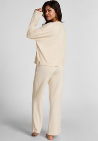 Crème-kleurig loungewearset met een vrijvallende top met brede mouwen en een rechte broek, gemaakt van zachte, gestructureerde stof.
