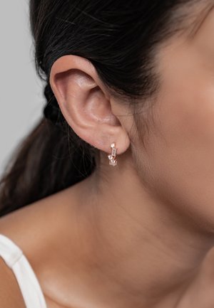 Rose gold hoop earrings featuring clear gemstones, set in a linear design, showcasing a shiny finish and modern geometric accents.