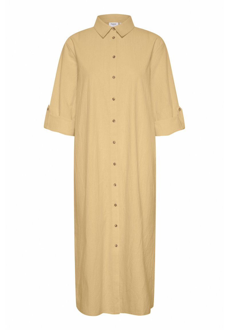 Robe chemise couleur beige clair, longueur genou, avec un col pointu, fermeture à boutons, manches retroussées et une texture de tissu lisse.