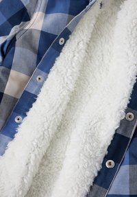 Flanellen jasje met een blauw en grijs geruit patroon, zachte, witte, pluizige voering en zilveren drukknoopjes.