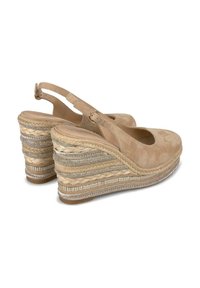 Beige wedge sandalen met een suède bovenkant en een open hiel. De wedge heeft gevlochten jute en metalen accenten langs de basis.