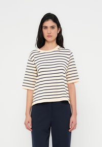 Ριγέ κοντομάνικη μπλούζα σε παστέλ ροδάκινο με μπλε σκούρες ρίγες; στρογγυλή λαιμόκοψη; χαλαρή εφαρμογή; υφή βαμβακερού υλικού με ελαφριά ελαστικότητα.