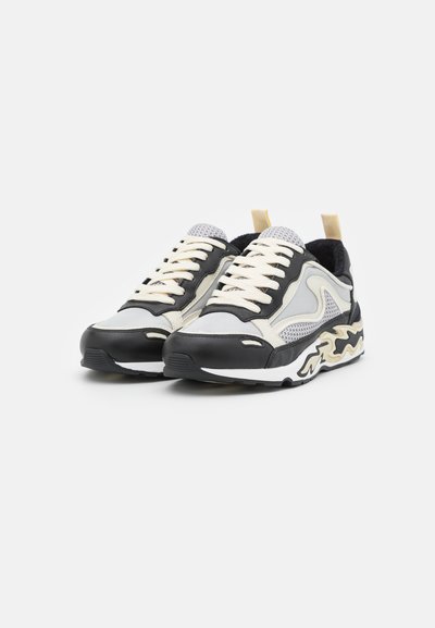 Baskets noires, grises et crème en matériau mesh et cuir. Semelle en caoutchouc blanche épaisse avec des accents de design abstrait. Lacets plats.