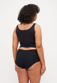 Black ribbed tank top with rounded neckline and matching high-waisted underwear featuring scalloped edges, viewed from the back.