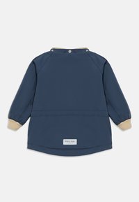 Temno modra vodoodporna jakna z dolgimi rokavi, bež pletenimi zapestnimi manšetami in rebrastim ovratnikom. Ima majhno oznako blagovne znamke na robu.