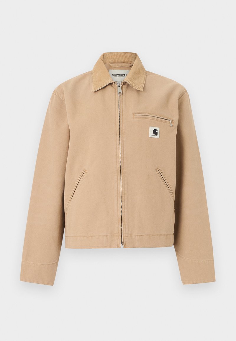 Beige workwear jacket with front zipper, corduroy collar, side pockets, and zippered chest pocket with Carhartt logo patch.