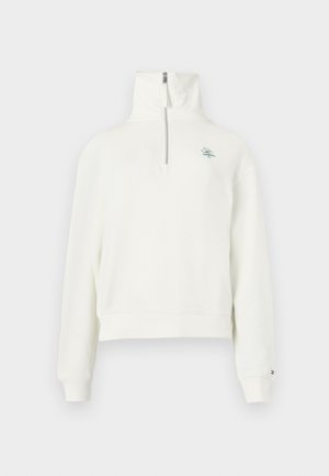 Biały polarowy sweter z wysokim kołnierzem, półzapięciem na zamek oraz haftowanym logo na klatce piersiowej. Posiada ściągacze na mankietach i luźny krój.