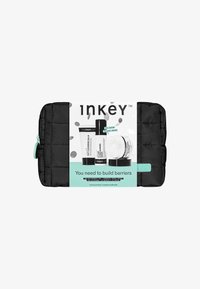 Black quilted cosmetic pouch with mint green accents containing three skincare products. Includes cleansers and a moisturizer, with prominent branding.