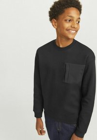 Svart tröja med lång ärm, rund halsringning och bröstficka. Tillverkad av mjukt tyg, med en slät yta och figurnära passform.