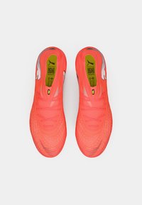 Lyse neonpink fodboldstøvler med tekstureret overdel, sorte detaljer og et PUMA-logo. Har et lavprofildesign og snørelukning.