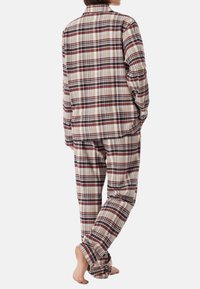 Pajamas w kratkę w miękkim materiale, z koszulą zapinaną na guziki z kołnierzykiem i dopasowanymi spodniami, w odcieniach brązu, kremu i burgundowego.