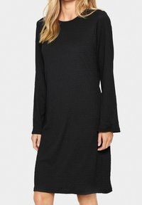 Svart långärmad klänning med ribbad textur, rund halsringning och avslappnad passform, som slutar strax ovanför knäna. Inga synliga mönster eller accenter.