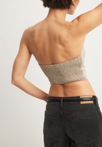 Bež crop top smockitud tekstuuriga, ühendatud mustade kõrge vöökohaga teksadega, millel on kaks tagakotti ja nahkdetailid vöö kohas.