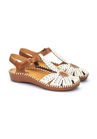 Sandales en cuir marron et crème avec un design floral découpé, des accents bruns et des détails cousus le long des bords. Semelles à talon bas.