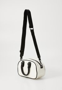 White synthetic bag with black accents, dual top handles, and a removable shoulder strap. Rounded shape with zipper closure on top.