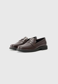 Braune Lederloafer mit glatter Oberfläche, ausgestattet mit einem Frontriemen und einer niedrigen schwarzen Gummisohle. Klassisches Schlupfdesign.